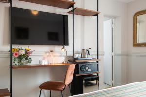 a bedroom with a desk with a chair and a television at Hôtel De La Porte Dorée in Paris