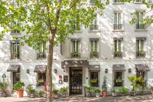 a white building with a tree in front of it at H&ocirc;tel De La Porte Dor&eacute;e in Paris