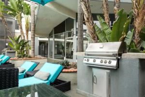 a grill on a patio with chairs and tables at Modern and Stylish Studio at 1200 Riverside in Burbank in Burbank
