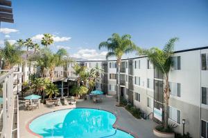 an apartment building with a swimming pool and palm trees at Modern and Stylish Studio at 1200 Riverside in Burbank in Burbank
