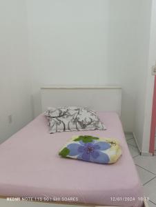 a white bed with a flower pillow on it at Pousada Brisamar Morro dos Conventos in Conventos