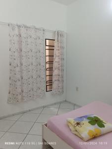 Cette chambre comprend un lit et une fenêtre avec des rideaux. dans l'établissement Pousada Brisamar Morro dos Conventos, à Conventos