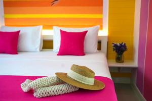 a hat sitting on a bed with pink pillows at LOVE beach club Koh Samui in Chaweng