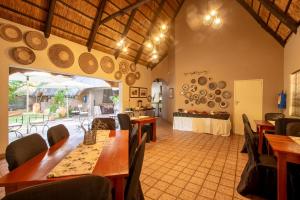 a dining room with wooden tables and chairs at Nguni Lodge in Victoria Falls