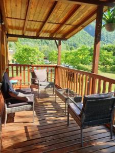 une terrasse couverte avec des chaises et des tables sur une terrasse en bois dans l'établissement Brevar Vakantie - Porlezza, à Porlezza