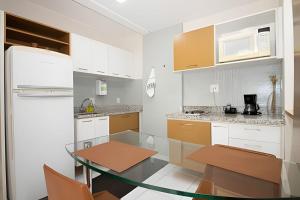 ブラジリアにあるHotel Premier Residence Brasília - Ozped Flatsの白いキャビネットとガラスのテーブル付きのキッチン