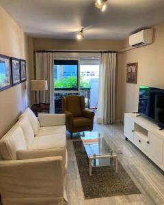 een woonkamer met een witte bank en een tv bij Casa Coral Fancy apartment at the beach in Torrox Costa