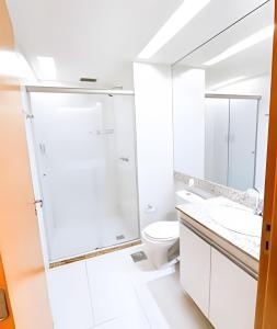 a white bathroom with a toilet and a mirror at Hotel Saint Moritz Brasília - Ozped Flats in Brasília