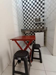 a table and stools in a kitchen with a checkered wall at Pousada Gil in Olímpia
