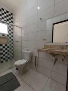 een badkamer met een toilet, een wastafel en een spiegel bij Pousada Gil in Olímpia