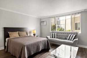 a bedroom with a bed and a couch and a window at Modern and Stylish Studio at 1200 Riverside in Burbank in Burbank