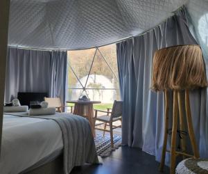 a bedroom with a bed and a large window at River Glamping Kalopanayiotis in Kalopanayiotis