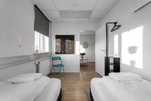 2 camas en una habitación blanca con silla azul en Bank Guesthouse by KEF Airport en Keflavík