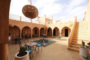 un patio con piscina, mesas y sillas en Maison Hassan Merzouga, en Merzouga