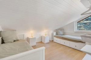 a white room with two beds and a window at Luxus-Wellness-Haus am Waldsee in Rieden