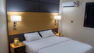 a bedroom with a white bed with two night stands at Complexe Hôtelier Sabah in Nouakchott +59 photos