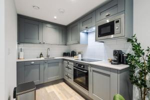 a kitchen with gray cabinets and a microwave at No.44 - Deluxe 2-Bedroom Duplex with Balcony in Stoney Middleton +38 photos