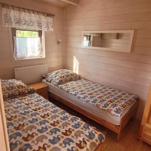 - 2 lits dans une chambre dotée de murs en bois dans l'établissement Domki pod lasem, à Rokiciny Podhalanskie