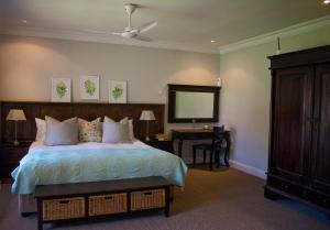 a bedroom with a bed and a table and a mirror at African Sands B&B in Amanzimtoti +71 photos