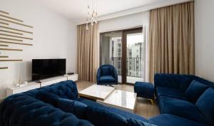 een woonkamer met een blauwe bank en een tv bij Manzil - 2BR Family Styled Apartment in Dubai Creek with Beach Access in Dubai