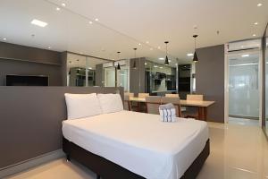 a bedroom with a white bed and a dining room at Hotel Vision Brasília - Ozped Flats in Brasilia