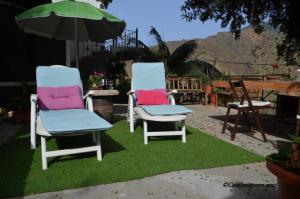 deux chaises assises sur l'herbe avec un parasol dans l'établissement Casa rural con Wifi y estupenda vista a la montaña en Hermigua, à Hermigua