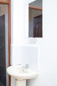 a bathroom with a white sink and a mirror at House of L in Eldoret