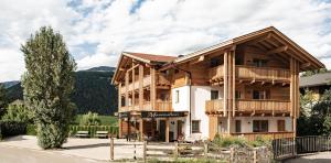 ein großes Holzgebäude mit einem Baum in der Unterkunft Residence Maximilian in Olang