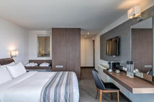 アテネにあるザ スタンレーのベッドとデスクが備わるホテルルームです。