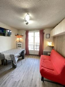 a living room with a red couch and a bed at Appartement risoul, 1 pièce , 4 personnes in Risoul