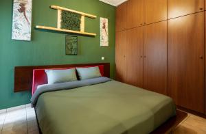 - une chambre avec un lit et un mur vert dans l'établissement GPX-CLR TheGreenFamilySuite, à Larissa