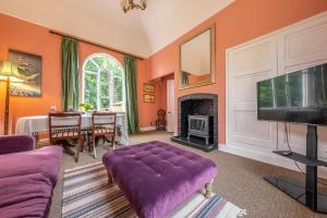 a living room with a purple couch and a tv at The Gate House in Wymondham