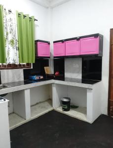 cocina con armarios de color rosa y verde en una habitación en Villa kandupamula, en Mirissa