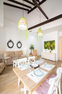 uma sala de estar branca com uma mesa de madeira e cadeiras em Apartamento Jazmín em Málaga