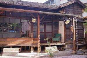 a wooden house with a porch and a green chair at 台中包棟百年日式老宅 請先致電詢問日期 in Taichung