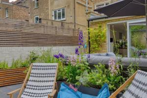 a patio with two chairs and a garden with flowers at Modern self-contained Studio with own access in Stroud Green in London