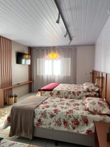 a bedroom with a bed with a floral bedspread at La Vita hospedaria studio verde in Nova Veneza