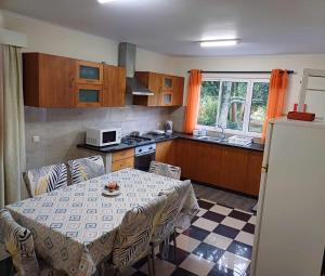 Una cocina con una mesa con sillas y un refrigerador. en Quinta das rãs, en Ponta Delgada