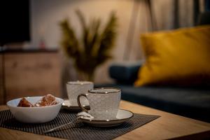 a table with two cups and a bowl of food at Apartments Częstochowa - Nova Bursa - Prywatny parking! in Częstochowa