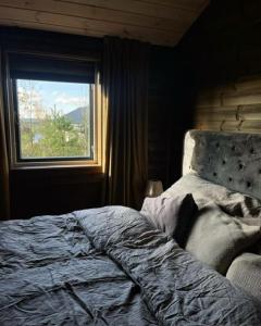 an unmade bed in a bedroom with a window at Moderne hytte med badstue in Rømskog
