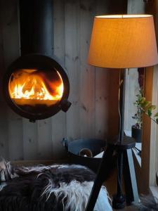 una lampada e un forno a fuoco in una stanza di Moderne hytte med badstue a Rømskog