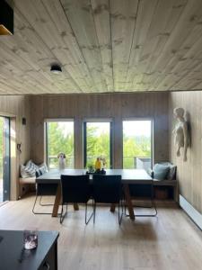 a living room with a table and chairs and windows at Moderne hytte ved sjøen med badstue in Rømskog