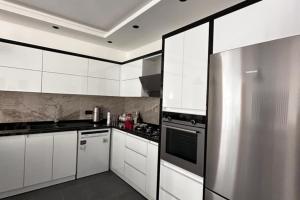 uma cozinha com armários brancos e um frigorífico de aço inoxidável em Villa Serengeti / Kalkan em Kas