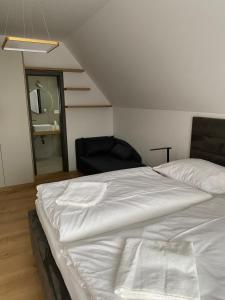 una camera con un grande letto bianco e una sedia di JAMY HOUSE Apartmán a Habovka