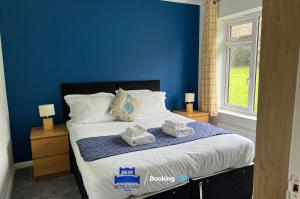 a blue bedroom with a bed with towels on it at 3 Bedroom Cosy Bungalow By Beds Away Short Lets & Serviced Accommodation Chalgrove With Outdoor Dining Area 