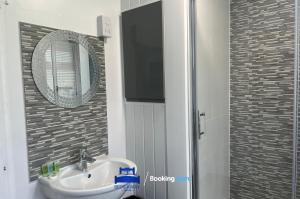 a bathroom with a sink and a mirror and a shower at 3 Bedroom Cosy Bungalow By Beds Away Short Lets & Serviced Accommodation Chalgrove With Outdoor Dining Area 