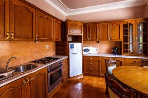 a kitchen with wooden cabinets and a white refrigerator at Mórocz Vendégház in Balatonboglár
