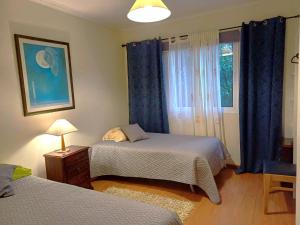 1 dormitorio con 2 camas y una ventana con cortinas azules en Quinta das rãs, en Ponta Delgada