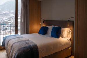 - une chambre avec un lit doté d'oreillers bleus et d'une fenêtre dans l'établissement ISARD RESIDENCES & SPA by Elegant Residences, au Tarter