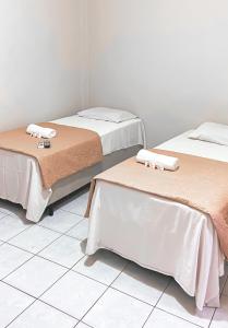 2 Betten in einem Zimmer mit weißen Fliesenböden in der Unterkunft SÃO CRISTOVÃO HOTEL in São Luís